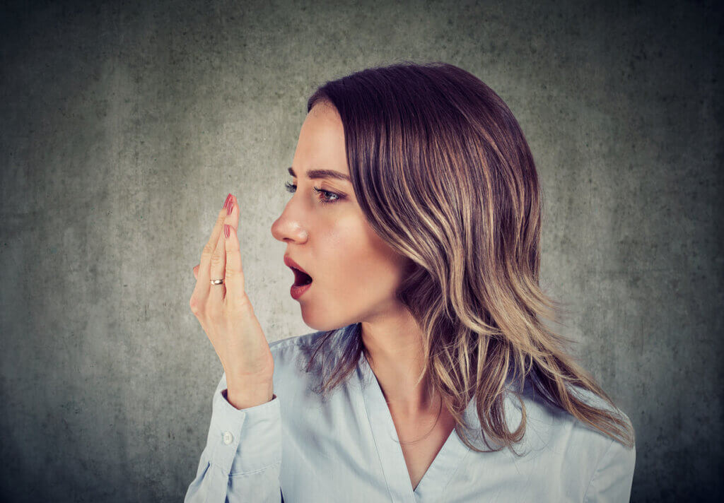 a woman blowing in her palm to smell her breath