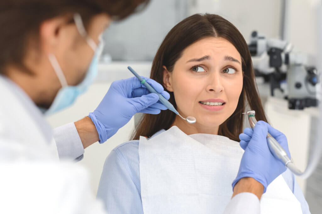  photo of a woman showing fear while receiving dental treatment