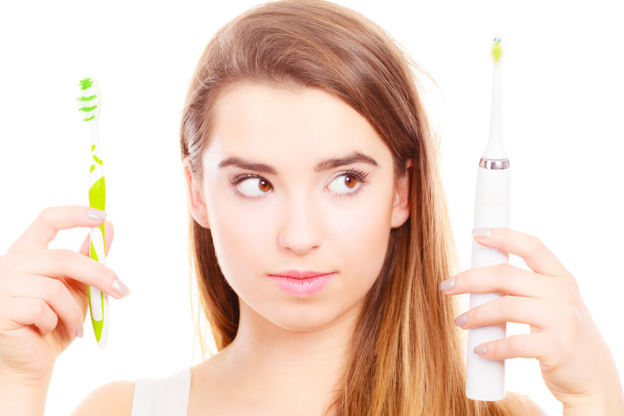Woman holding, choosing between electric and traditional toothbrush, have to make decision what is best for teeth.