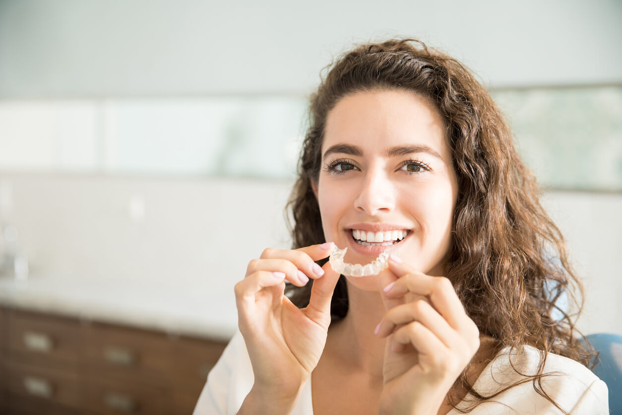 A woman holding an Invisalign aligner tray