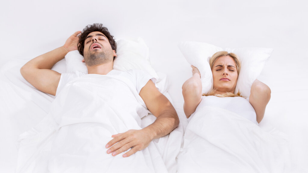 man and woman sleeping. Man is snoring.