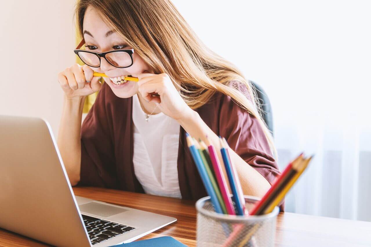 Woman experiencing stress in front of a computer and biting on a pencil